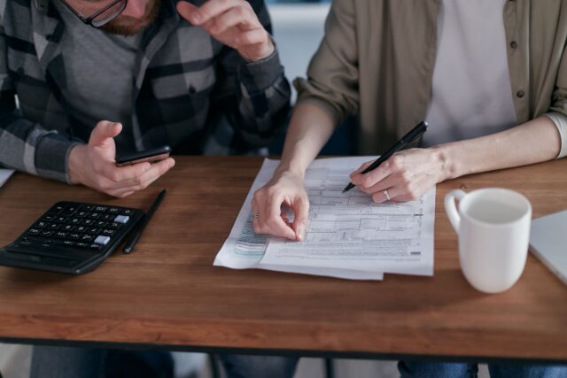 Factură la energie electrică pe o masă, alături de un calculator și un pix, lângă un contor