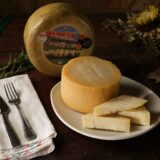 Pită rotundă de casă, cu coajă aurie, așezată pe un ștergar de in, lângă un castron cu făină